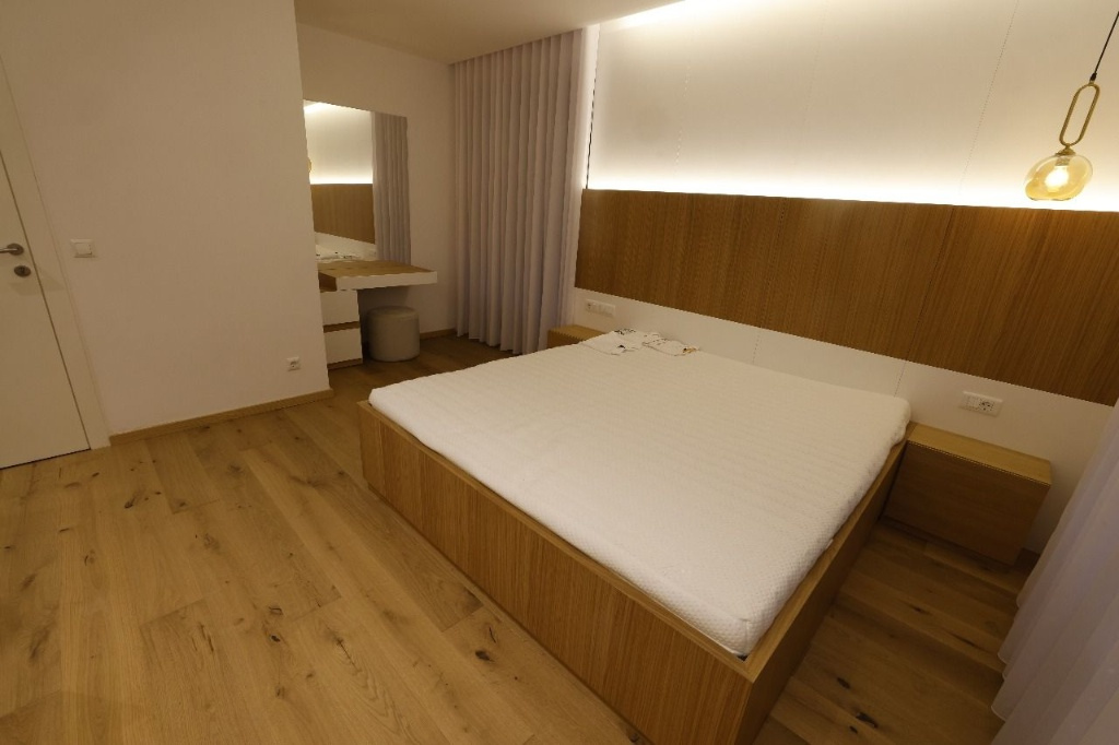 Natural wood bed frame with backlit wood headboard and integrated nightstands