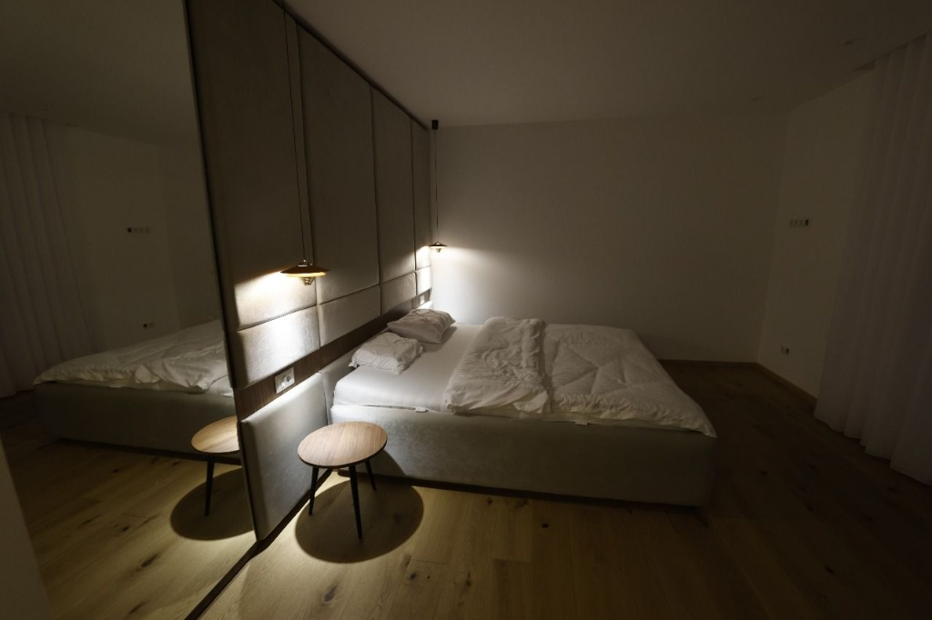 Modern low-profile bed with full-height upholstered headboard panels and pendant lighting