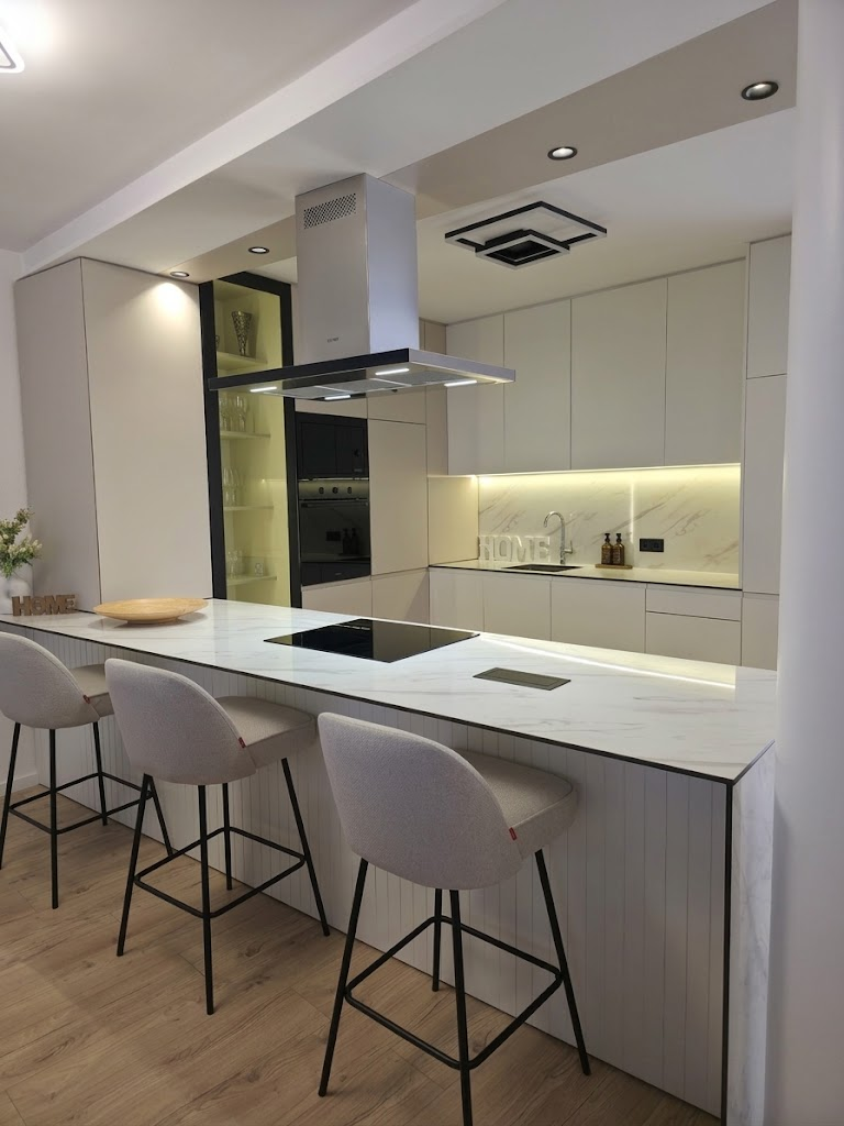 Minimalist white handleless kitchen with marble countertop and integrated induction cooktop