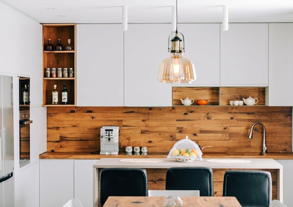 White handleless kitchen with a light wood island, oak backsplash and open oak shelving